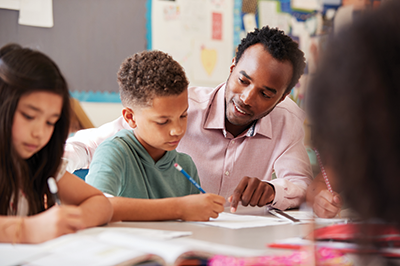 Smiling male teacher assisting boy and a girl